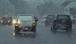 Foto de temporal com chuva intensa, com pontos de alagamento nas ruas e tráfego lento.