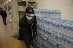 Coca-Cola, doação de água. Um homem usa máscara e separa garrafas de água.