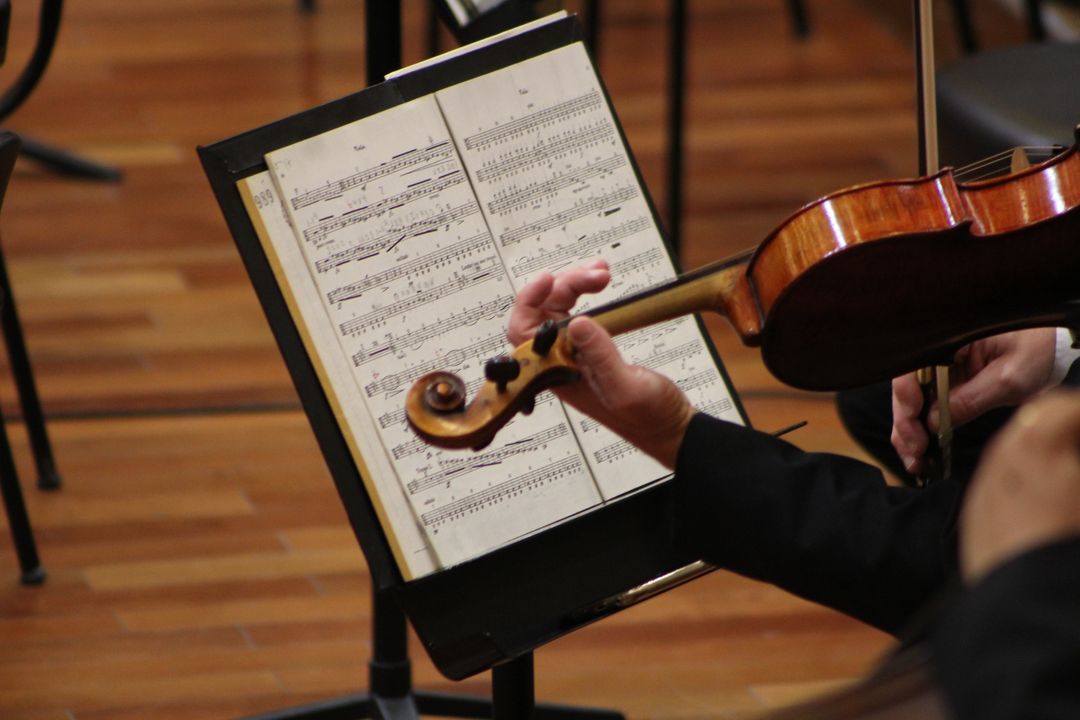 Mozart e Dvořák; partitura e braço de uma pessoa tocando violino.