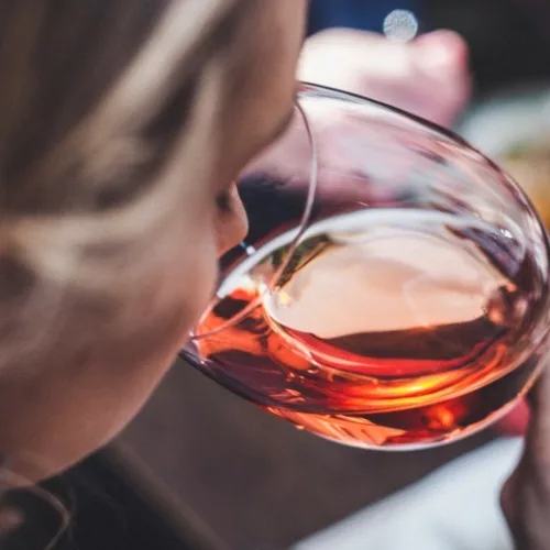 Mulher cheira vinho na taça da Vineria.