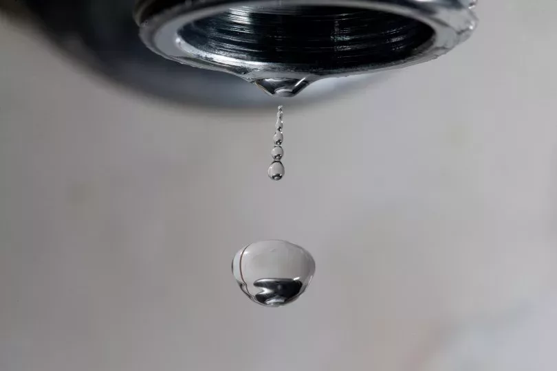 Pingo de água caindo de uma torneira sendo fechada
