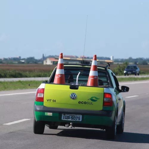 Caminhonete Volkswagen Saveiro, na cor verde limão e verde floresta, pertencente à Ecosul. Veículo posui a inscrição "VIT 04", está sobre uma estrada no Pedágio de Capão Seco e carrega dois cones laranjas na caçamba.