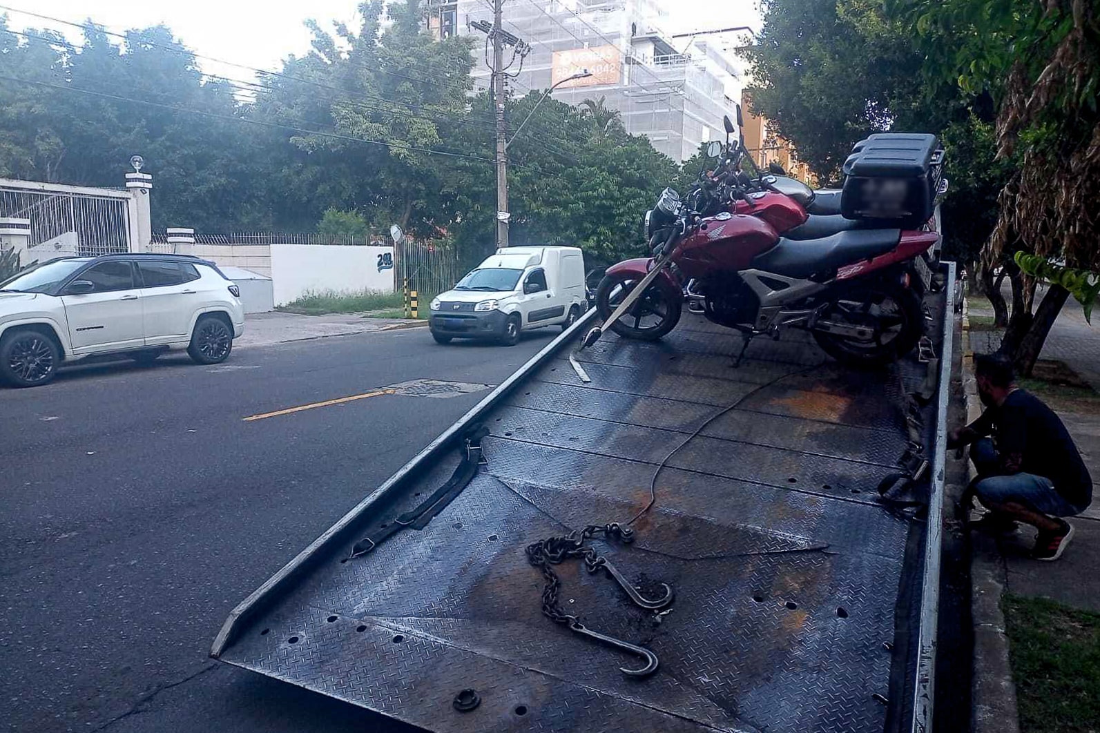 Três motocicletas apreendidas durante blitz em Porto Alegre são colocadas em cima de plataforma.
